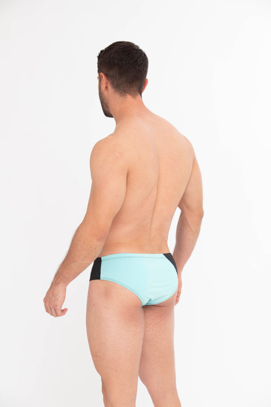 Man wearing light blue swim briefs on a white background