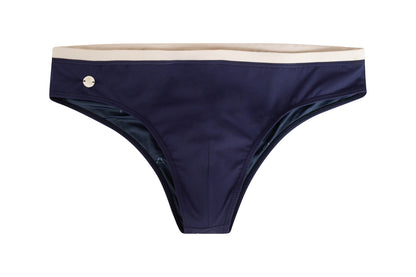 A navy blue swim brief with a sandy white waistband and a small logo on the left side.