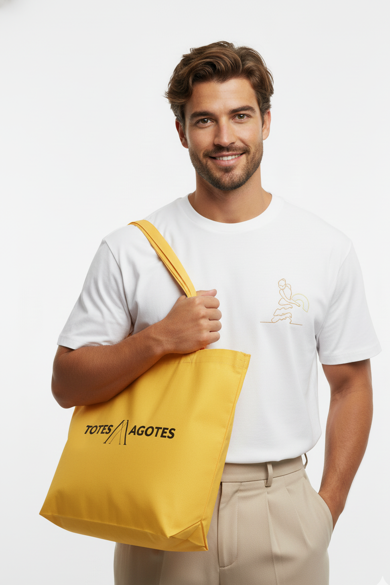 Man holding a yellow tote bag with 'Totes Agotes' branding against a white background