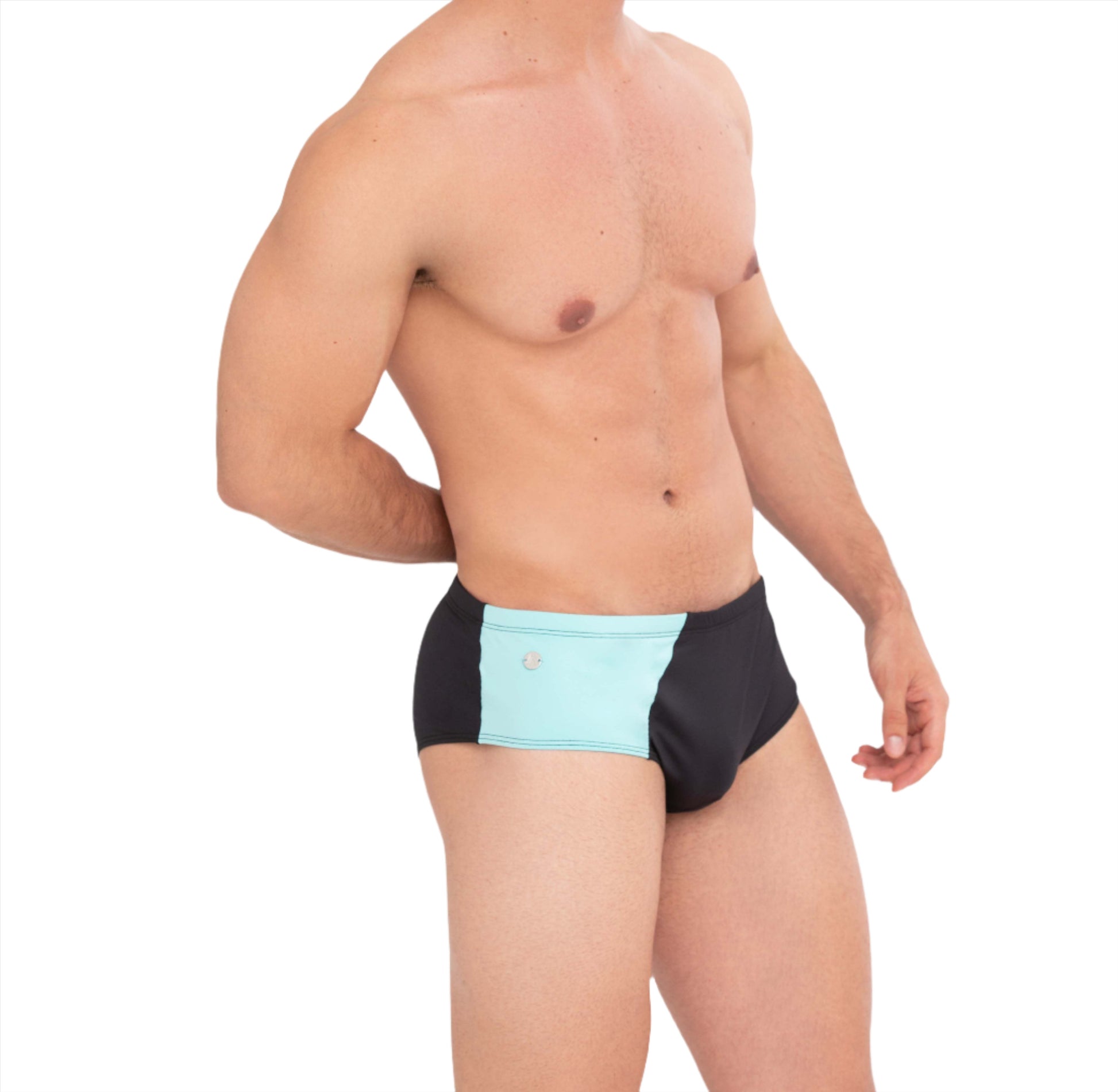 This image features a side view of a male model sporting the Athletic Swim Brief, a stylish hybrid of traditional briefs and sungas. The swimsuit is designed with a striking color block pattern in glacier blue and volcanic black, inspired by the contrasting landscapes of Diamond Beach in Iceland.