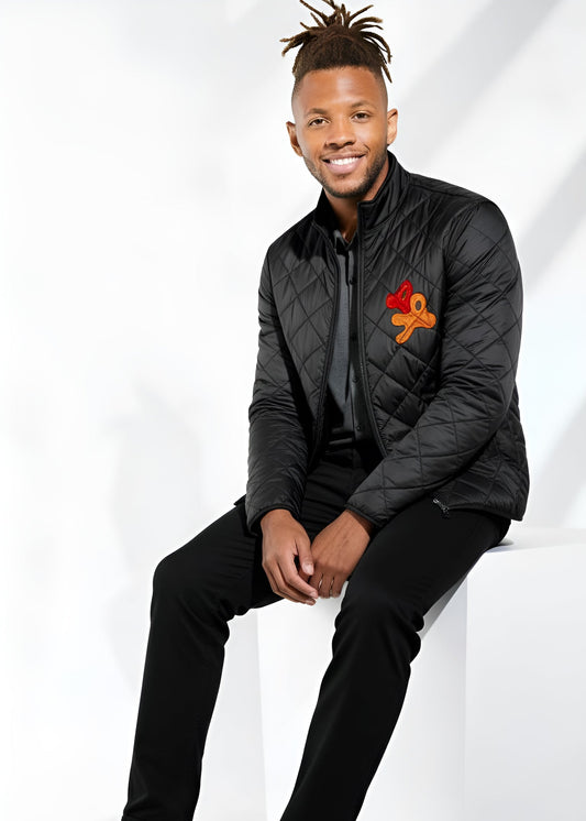 Man wearing a black quilted jacket with a logo, sitting on a white surface.