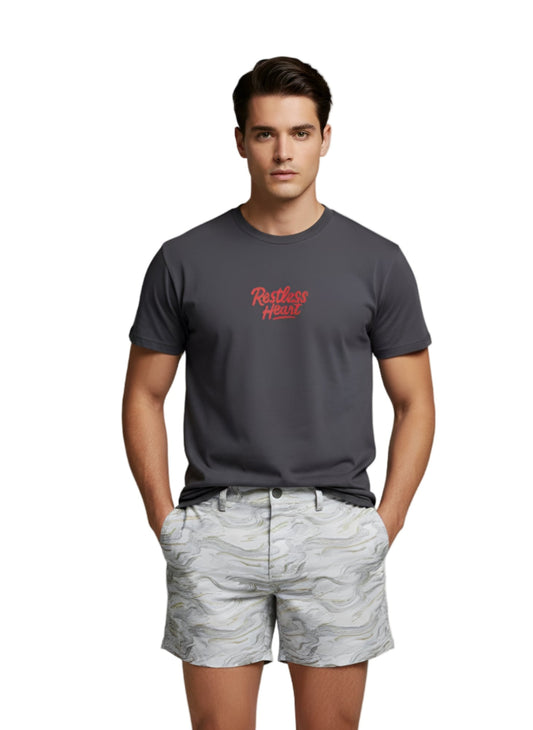 Man wearing a dark gray t-shirt with red text and light gray camouflage shorts on a plain background